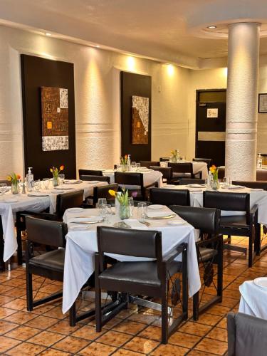 Fresnillo de González EcheverríaHotel del Fresno的用餐室配有白色桌子和黑色椅子