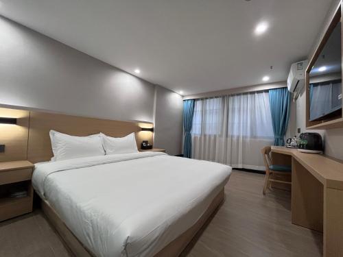 广州布丁酒店（广州洛溪地铁站店)的卧室配有一张白色大床和一张书桌