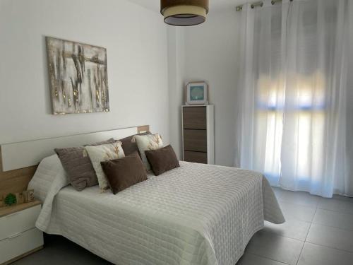 马拉加piso recinto ferial en teatinos的一间卧室配有一张大床,配有白色床单和棕色枕头