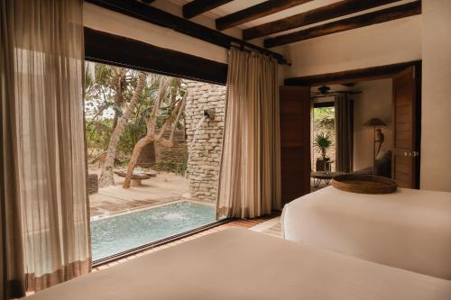 图卢姆Aldea Canzul Tulum的卧室设有窗户,享有游泳池的景色