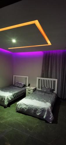 阿古拉耶特منتجع سمايل的紫色灯房内的两张床