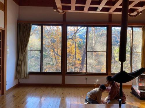 伊那市Irori 新山ふるさと体験館的两个孩子在带大窗户的房间玩耍