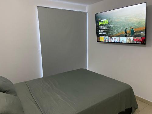 库库塔Habitación en Apartamento amplio cómodo y equipado的卧室配有壁挂式平面电视。