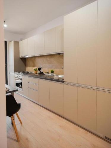 巴克乌Apartament de lux Bacău的一间铺有木地板的大厨房,配有白色的橱柜