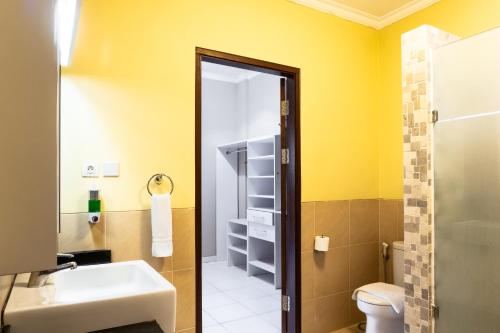 Bentakan KecilLA CASA BORNEO的一间带水槽和卫生间的浴室以及黄色的墙壁。