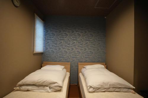 本宫Guest House Takiyoshi的小型客房的两张床,设有蓝色的墙壁