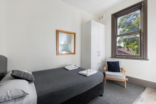 悉尼Falcon Lodge的一间卧室设有一张床、一个窗口和一把椅子