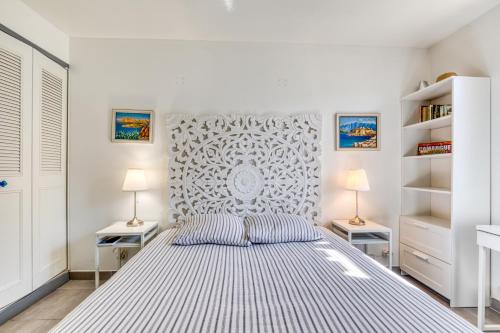 帕拉瓦莱弗洛Les Palmiers的一间白色卧室,配有一张床和两盏灯