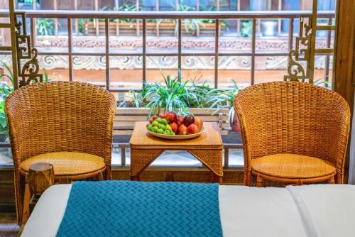 丽江思法特观景客栈 Sifat Viewing Inn的桌上一碗水果和两把椅子