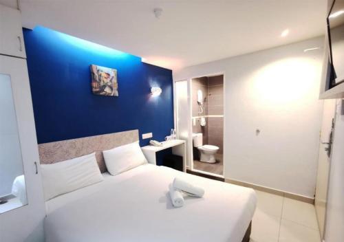 吉隆坡Mozu Hotel Sri Hartamas的卧室配有白色的床和蓝色的墙壁