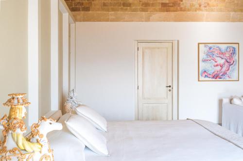 马泰拉Masseria Fontana di Vite的白色卧室配有白色的床和马床头板