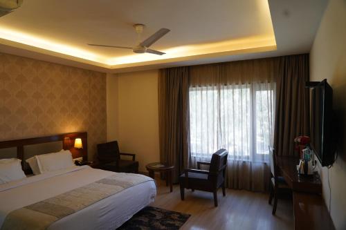 德拉敦Hotel Forest Avenue - Best Luxury Hotel in Dehradun的配有一张床、一张书桌和一扇窗户的酒店客房