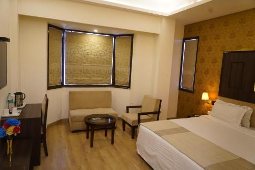 德拉敦Hotel Forest Avenue - Best Luxury Hotel in Dehradun的配有床、椅子和桌子的酒店客房