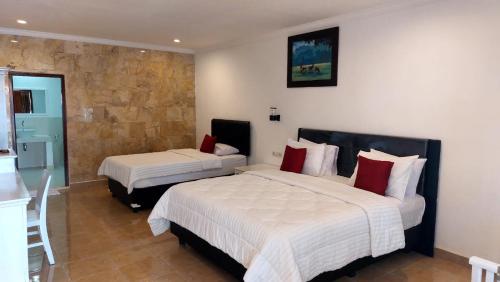 罗威那Grand Melka Hotel的酒店客房设有两张床和石墙。