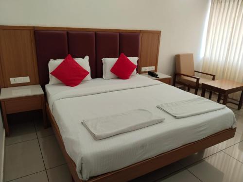 乌杜皮Hotel Janardana的一间卧室配有一张带红色枕头的大床