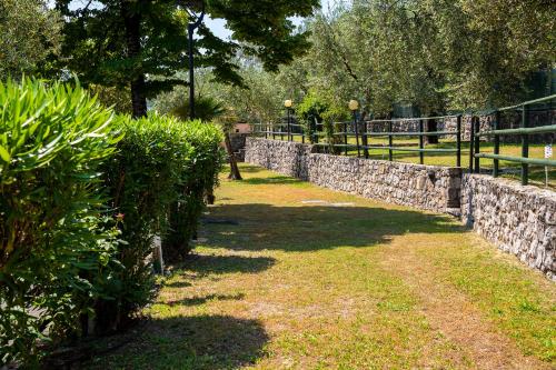 托斯科拉诺-马德尔诺Camping Toscolano的石墙,有灌木和围栏