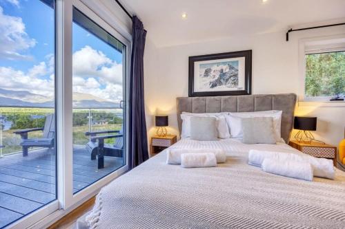 HayfieldNew Build Lodge With Stunning Views of Loch Awe的一间带大床的卧室和一个阳台