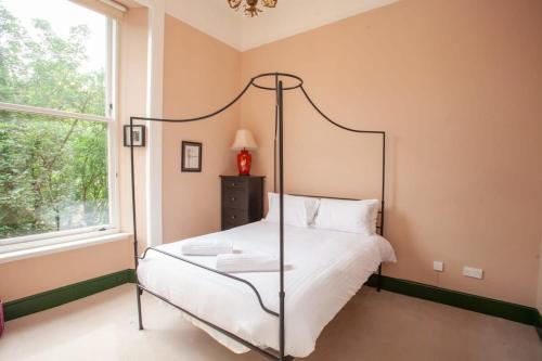 格拉斯哥Bright Spacious 3 Bed Flat的一间卧室设有四柱床和窗户。