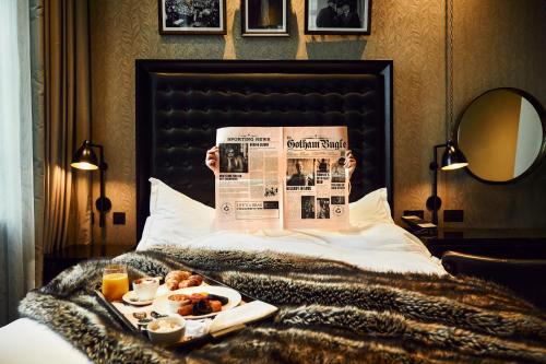 曼彻斯特哥谭酒店的躺在床上,有报纸和食物的人