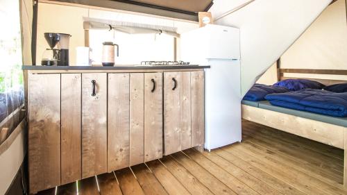 ÅnimskogIngerichte safaritenten aan Zweeds meer op Betteld Sweden的一个带木制橱柜的厨房和一张位于客房内的床