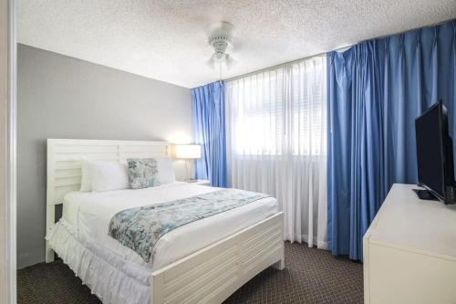 基韦斯特The Barbados by Brightwild-Bright Condo w Pool的一间卧室配有床和蓝色窗帘的窗户