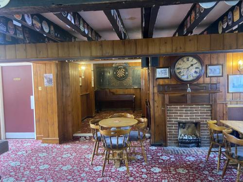 格雷夫森德The Jolly Drayman Pub and Hotel的一间设有桌子、壁炉和时钟的房间