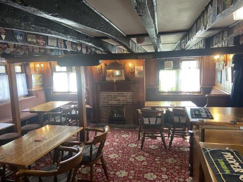 格雷夫森德The Jolly Drayman Pub and Hotel的一间带桌椅和壁炉的餐厅