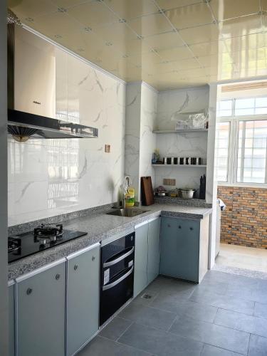 海口Cozy home of Orchid的厨房设有白色的墙壁和灰色的台面