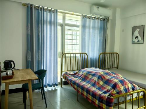 海口Cozy home of Orchid的一间卧室配有一张床、一张桌子和一个窗户。