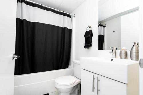 温尼伯Premium 2BD Loft DT Heated Parking Rooftop Patio BBQ Gym Coffee的浴室设有白色卫生间和黑色淋浴帘。