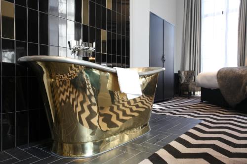 曼彻斯特哥谭酒店的浴室设有黑色瓷砖,配有金色浴缸。