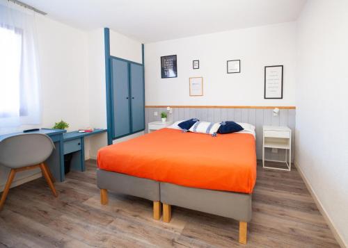 比斯卡罗斯亚特兰迪德酒店的一间卧室配有一张橙色的床和一张书桌