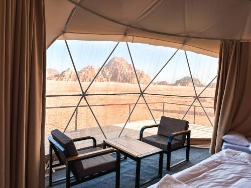 瓦迪拉姆Mirage Camp Wadi Rum的帐篷配有1张床、2把椅子和1张桌子