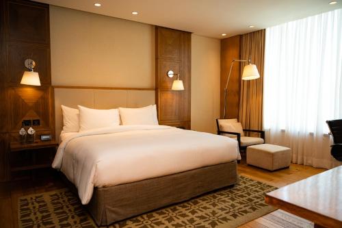 浦那DoubleTree by Hilton-Pune Chinchwad的卧室配有一张白色大床和一把椅子