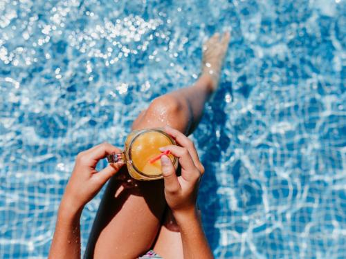 马贝拉VACATION MARBELLA I Villa Sirio, Golf-Front Villa, Private Pool, Privacy的妇女在游泳池前喝一杯