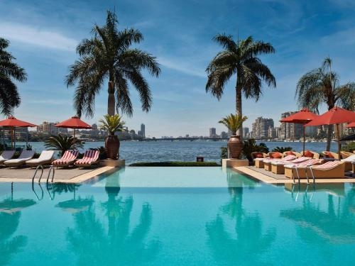 开罗开罗尼罗河厄尔盖兹拉索菲特酒店的游泳池设有椅子和棕榈树,水源