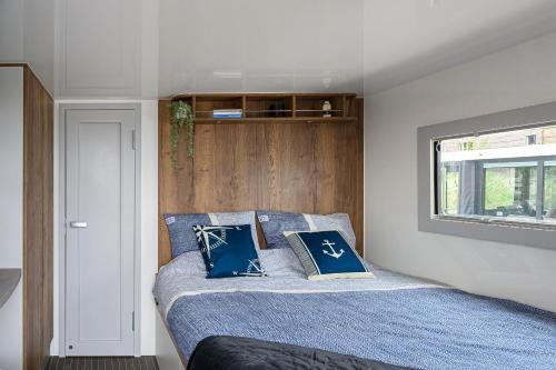 泽沃德Olav Boats Houseboot的一间卧室配有一张带蓝色床单的床和一扇窗户。