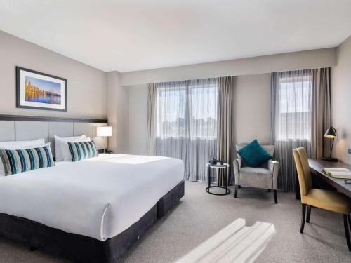 奥克兰The Sebel Auckland Manukau的酒店客房设有一张大床和一张书桌。