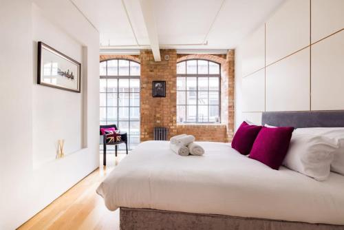 伦敦Central Soho Loft with A C & Concierge的卧室配有带红色枕头的大型白色床