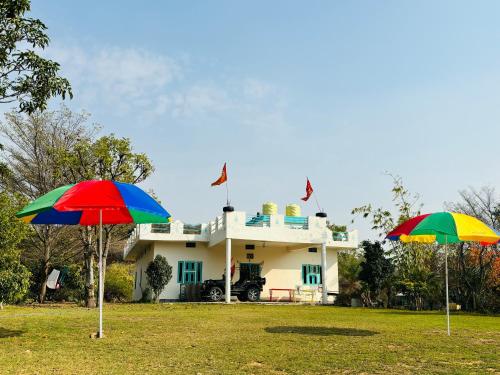 斋浦尔The Bainada farm的两把五彩缤纷的雨伞在房子前面