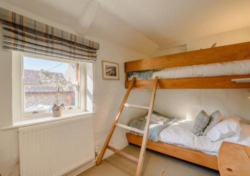 布莱克尼Parsley Cottage的一间卧室设有两张双层床和一扇窗户。