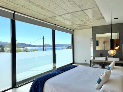 卡马里尼亚斯Hospedium Hotel Devalar Do Mar的一间卧室设有一张大床和一个大窗户