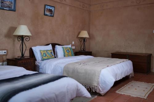 瓦尔扎扎特古堡卡斯巴酒店的一间卧室设有两张床,墙上有两盏灯。