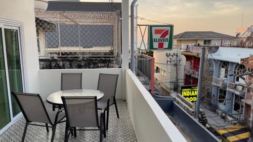 芭堤雅市中心Blue whale Hostel & Café的阳台的天井配有桌椅