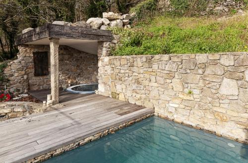 圣地亚哥－德孔波斯特拉Casa do Cebro Casa con piscina y jacuzzi privados的一座游泳池,其木甲板毗邻石墙
