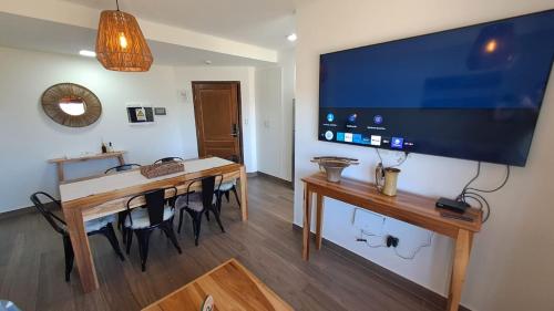 卡法亚特Alpine View Chalet Cafayate的一间用餐室,配有一张桌子和一台墙上的大电视