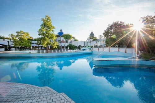 巴特布卢毛布鲁茂百水温泉大饭店的阳光反射在水中的游泳池