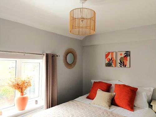 惠特彻奇Charming Terrace Home in Whitchurch的一间卧室配有一张带红色枕头的床和一扇窗户