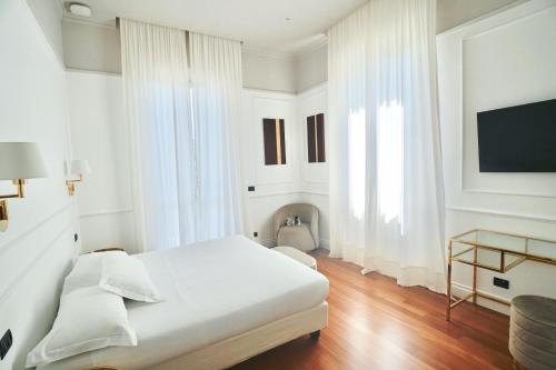 摩德纳雷齐吉公园酒店的一间白色卧室,配有床和电视