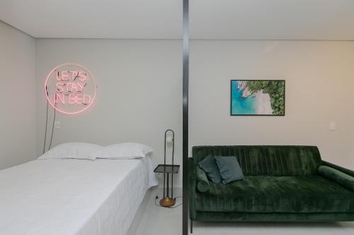 贝洛奥里藏特Apto no centro c/Ar Condicionado的一间卧室配有一张床和一张绿色沙发